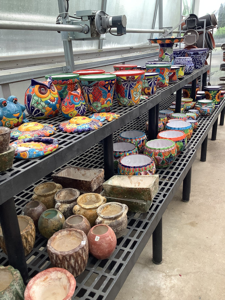 Two shelves filled with mostly Talavera pottery.